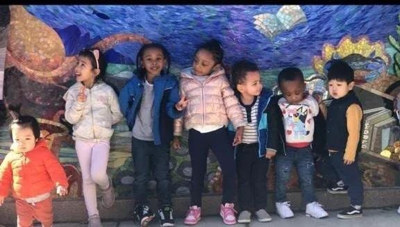 Children standing together in front of a colorful aquarium mural